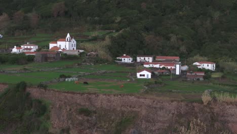 Side-panning-shot-of-white-church-at-small-town-at-Flores-island-Azores