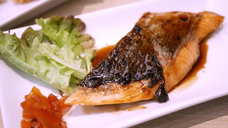 Panning-from-the-right-to-the-left-side-of-the-frame-showing-a-platter-of-grilled-salmon-steak,-glazed-with-teriyaki-sauce