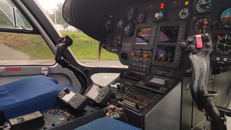 Interior-view-of-helicopter-cockpit-with-its-rudders-and-dashboard-and-navigation-and-communication-instruments-activated,-shot-traveling-backwards,-Santiago-de-Compostela,Galicia,Spain