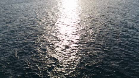 Slow-pullback-from-ray-of-sunlight-spread-on-open-Caribbean-ocean-water-at-sunset