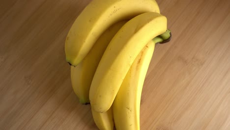 Banana-Bunch-Rotating-On-Wooden-Background