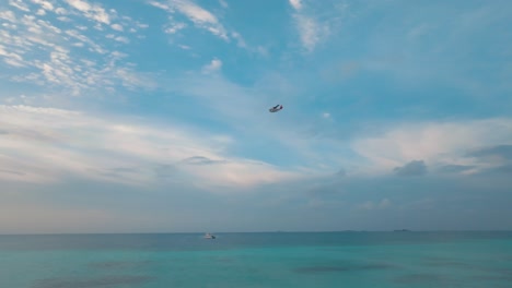 In-A-Tropical-Seascape-A-Boat-Sails-Towards-The-Beach-And-An-Aircraft-Flies-Above