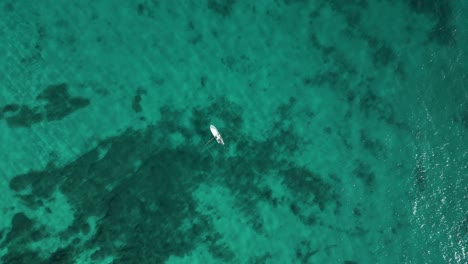 Slow-motion-top-down-aerial-view-of-fishing-boat-in-vast-open-ocean