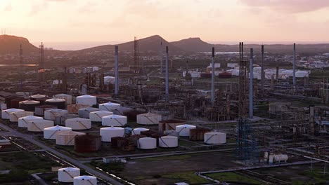 Aerial-orbit-around-oil-refinery-stacks-and-complex-network-pipes-at-sunset