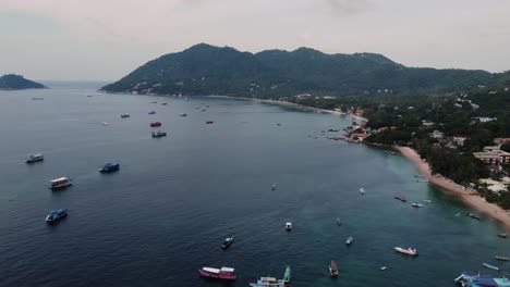 Aerial-drone-shot-of-Koh-Tao-Thailand-in-southeast-Asia,-with-diving-and-fishing-boats-in-the-bay-by-the-village