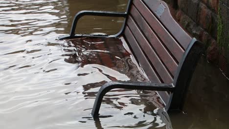 The-River-Severn-in-flood-with-water-covering-a-bench-on-its-banks-at-Bewdley,-Worcestershire