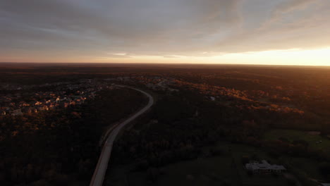 Wide-aerial-shot-over-an-American-suburb-at-sunset,-dolly-sideways-over-a-road
