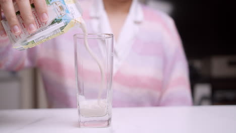 Detail-Einer-Frau,-Die-Milch-In-Eine-Glastasse-Gießt
