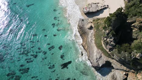 Flight-over-rocky-cliffs-and-turquoise-water-beach-of-Shirahama,-Japan
