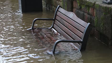 River-Severn-flood-water-covering-a-bench-on-its-banks-at-Bewdley,-Worcestershire