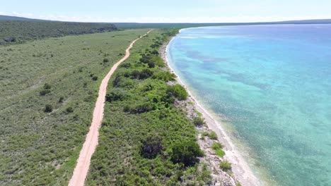 Aerial-flight-over-sandy-path-along-coastline-of-Bay-in-Pedernales-during-sunny-day