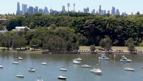Urban-skyline-viewed-over-a-tranquil-bay-dotted-with-sailboats,-A-perfect-blend-of-nature-and-city-life