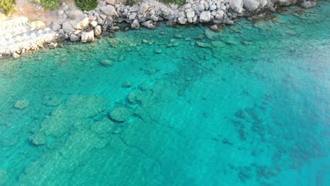 Vista-De-Drones-En-Grecia-Vista-Superior-Sobre-El-Mar-Azul-En-Loutro-Junto-A-Una-Colina-Rocosa-En-Un-Día-Soleado