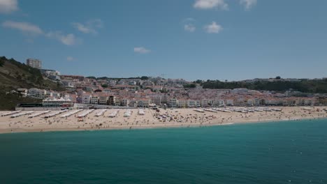 Panoramic-drone-shot-of-Nazaré-beach-from-the-sea-with-a-nice-view-of-the-city