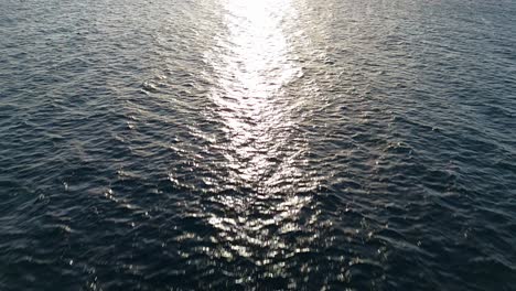 Ray-of-sunlight-spread-across-open-ocean-water-ripples-at-golden-hour