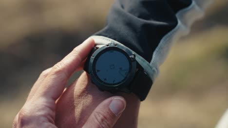 Man-checking-his-Garmin-watch-during-hike-in-the-mountains