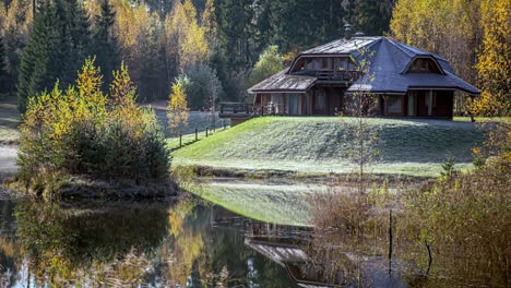 Hütte-An-Einem-Fluss-Im-Herbst-Mit-Herbstfarben-Und-Frost-Auf-Dem-Gras---Zeitraffer