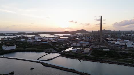 Drohne-Umkreist-Die-Ölraffinerie-Auf-Curaçao,-Während-Das-Letzte-Sonnenlicht-Die-Landschaft-Ziert