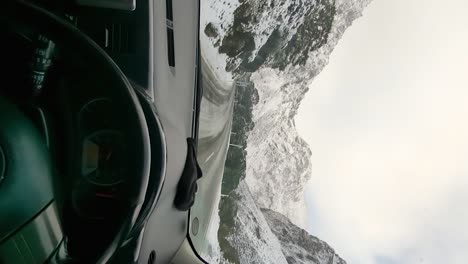Pov-driving-a-car-on-the-very-snowy-entrance-of-Mifrod-Sound-Fiord_vertical-view