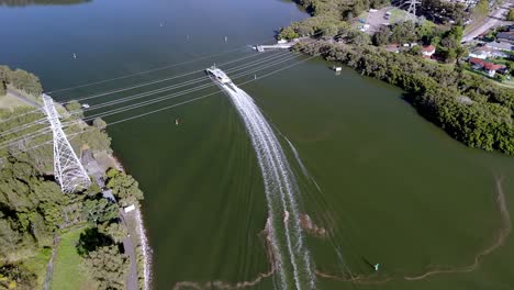 Dynamische-Luftperspektive:-Schnellboot-Fährt-Durch-Ruhige-Gewässer-In-Der-Nähe-Eines-üppigen-Flussufers