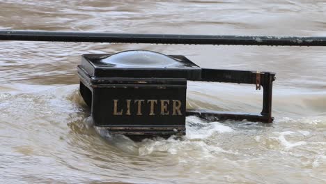 Fast-flowing-flood-water-overflowing-a-litter-bin-and-railings