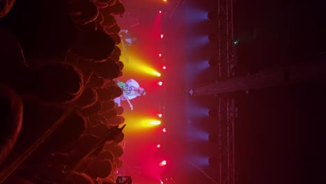Vertical-handheld-medium-shot-of-Jacob-Lee-Nicholas-Sullenger-playing-guitar,-singing,-and-performing-live-in-concert-as-the-band-Jawny-with-people-dancing-and-bright-colorful-stage-lights-flashing