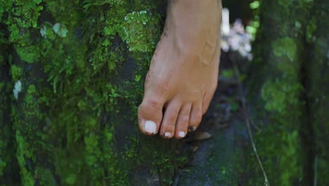 Naked-female-foot-with-white-painted-nails-caressing-a-tree-full-of-slime-in-the-middle-of-the-forest-and-nature