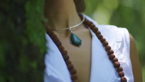 A-woman-wearing-a-beautiful-necklace-of-a-green-rock-hanging-from-her-neck-while-she-admires-nature-in-the-jungle