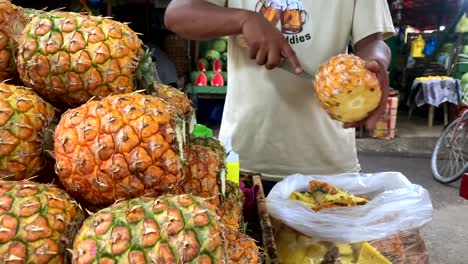 Ein-Philippinischer-Mann-Verkauft-Frische-Reife-Ananas-Und-Zeigt,-Wie-Man-Eine-Ananas-Einfach-Schält-Und-In-Scheiben-Schneidet