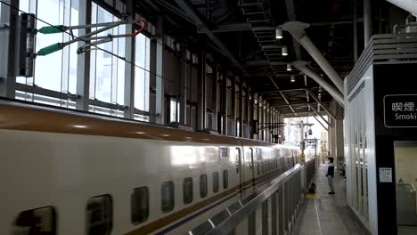 Arrival-of-a-modern-blue-train-on-the-Hokuriku-Shinkansen-line-inside-Toyama-station-in-Japan,-while-a-person-waits-to-board