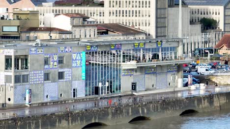 CAP-Sciences-children-education-museum-at-the-Garonne-River-shore-with-cyclists-passing-by,-Aerial-dolly-right-shot
