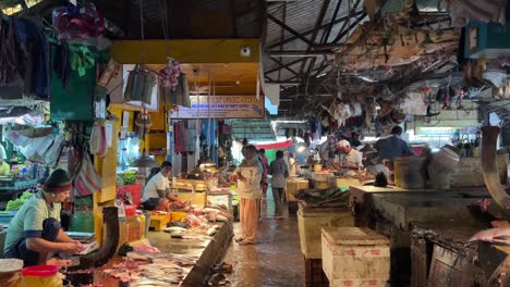Hardworking-sellers-selling-fishes-and-seafoods-to-customers-in-a-crowded-fish-market-in-Kolkata,-India