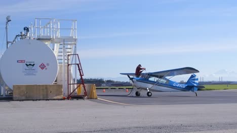 Pilot-on-Ladder-Fueling-High-Wing-Taildragger-Airplane-at-Fuel-Station