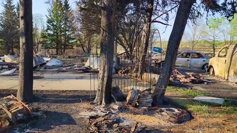 devastation-with-burnt-trees,-debris,-and-damaged-cars-after-a-huge-fire