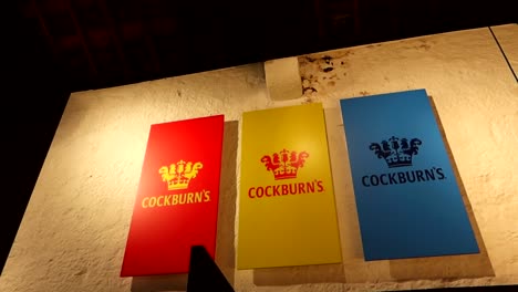 Colorful-logo-of-Cockburn's-wine-cellar-lit-by-light-in-cellar,-motion-view