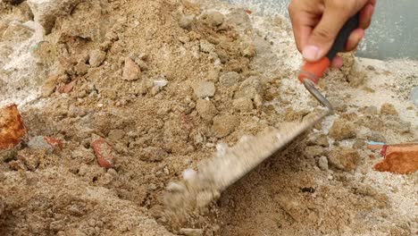 close-up-scooping-up-sand-with-a-small-shovel