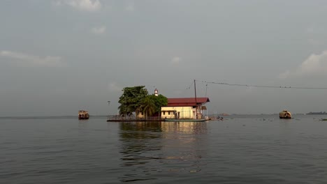 867-Kerala-Backwater-Day-A-big-house-is-visible-and-there-is-water-around-it-and-lots-of-boats-are-going