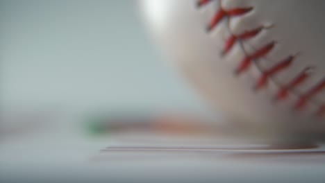 Cinematic-commercial-zoomed-in-macro-shot-of-a-rolling-white-base-ball,-close-up-on-red-stitches,-baseball-roll,-professional-studio-lighting,-smooth-slow-motion-120-fps-close-up