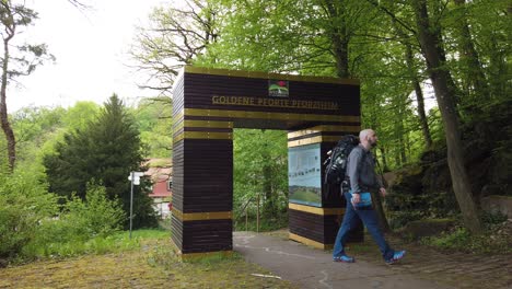 Male-hiker-passing-through-the-symbolic-gate-in-the-city-of-Pforzheim-starting-the-popular-long-distance-trail-Westweg-through-the-Black-Forest-in-southern-Germany