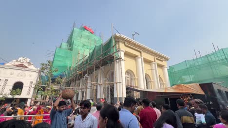 Wide-shot-of-devotees-visiting-Kalighat-temple-covered-in-green-cloth-for-construction-in-Kolkata,-India