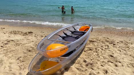 Two-transparent-clear-kayaks-at-a-sunny-beach-in-Cavalière-Lavandou-South-of-France,-fun-water-sport-holiday-vacation-activity-in-the-sea,-4K-shot