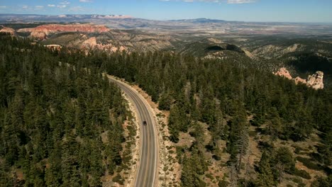 A-cinematic,-aerial,-drone-shots-of-the-scenic-beautiful-nature-with-a-Black-Ford-Mustang-traveling-on-the-highway
