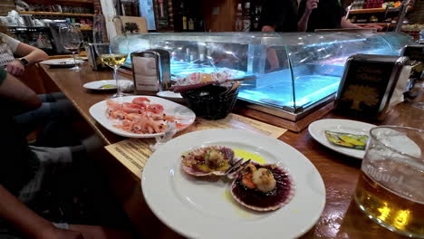 Person-enjoying-a-fresh-scallop-at-a-seafood-bar-in-Malaga,-Spain