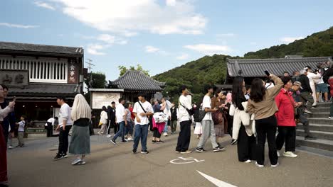 Large-group-of-tourists-traveling-and-visiting-the-roads-and-streets-of-an-ancient-temple-in-Japan,-learning-about-its-architecture,-culture-and-history
