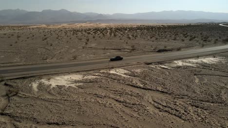 A-cinematic-aerial,-drone-shot-of-a-black-Ford-Mustang-traveling-on-the-road-in-the-middle-of-Death-Valley