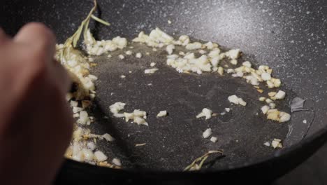 Chef-Frying-Garlic-with-Rosemary-In-Oil-On-Non-stick-Pan