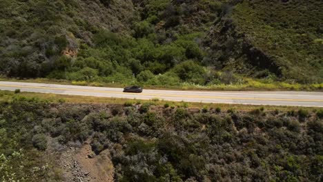 A-cinematic,-Aerial,-drone-shot-of-a-Convertible-Ford-Mustang-along-the-valley-and-mountain-peaks
