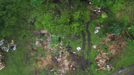 Aerial-descending-over-people-work-and-remove-garbage-from-countryside-yard