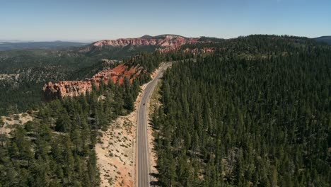 A-cinematic,-Aerial,-Drone-footage-of-an-unrecognizable-Ford-Mustang-traveling-on-the-highway-in-between-a-national-park-in-Bryce