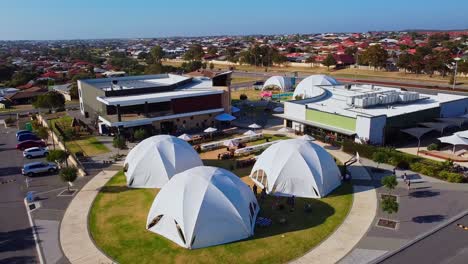 Aerial-pull-back-view-over-white-dome-tents-and-picnic-benches-setup-ready-for-outdoor-event